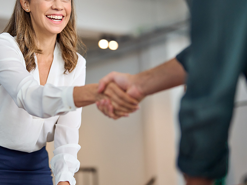 Smiling professional shaking hands with a client, symbolising the trusted partnership and value delivered through AMR energy meters and BMS audits.