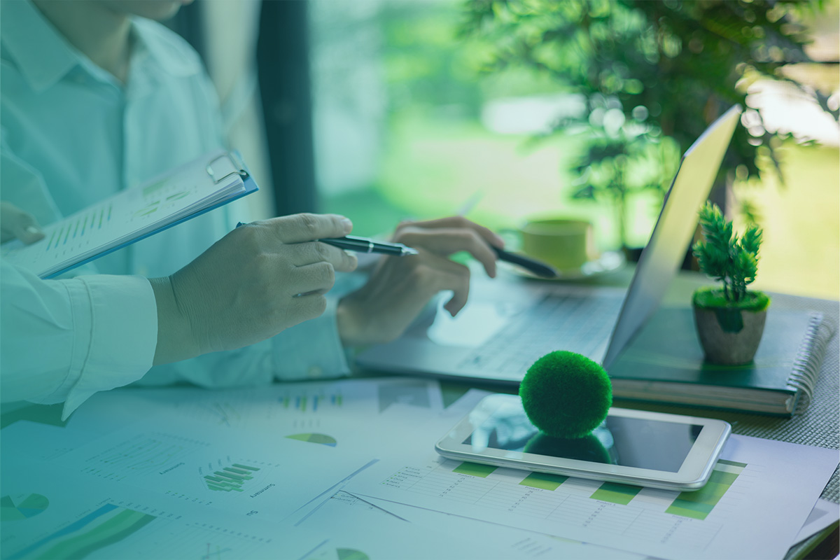 Professionals reviewing sustainability data, charts, and digital reports on laptops and tablets as part of CDP (Carbon Disclosure Project) and GHG (Greenhouse Gas) Reporting activities.