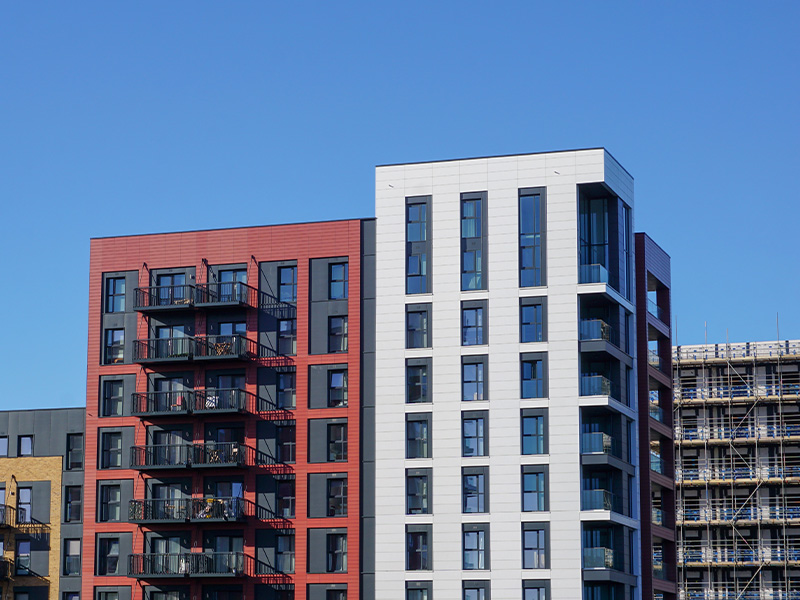 Modern residential apartment buildings against a clear blue sky, representing the benefits of basket energy procurement for housing groups and landlords.
