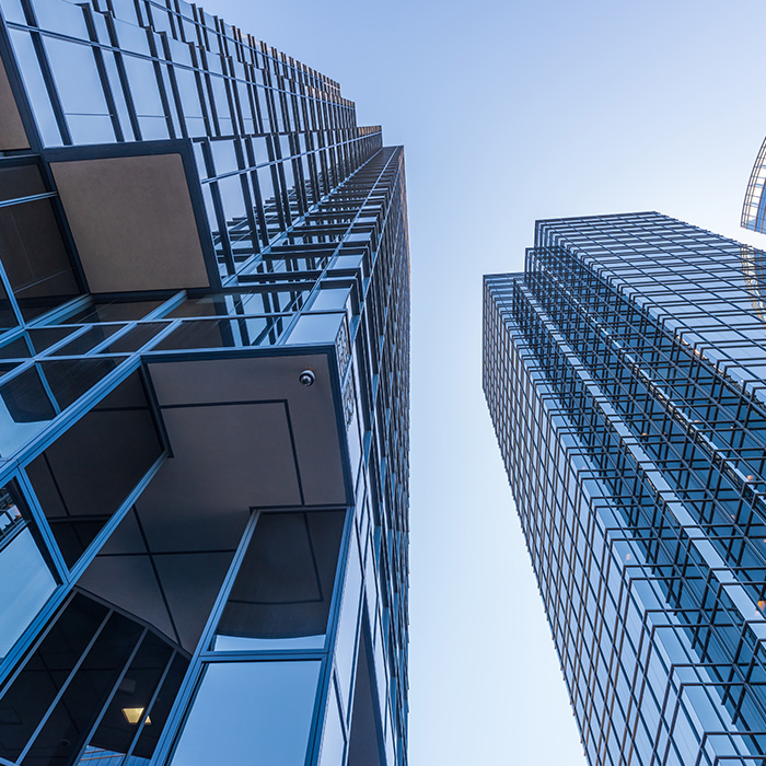 Upward view of modern glass skyscrapers, symbolising the need for a track and trace survey for commercial buildings to ensure accurate utility mapping and compliance.