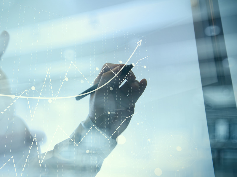 Hand drawing an upward trend line on a transparent screen, symbolising how energy market intelligence for procurement drives growth and sustainability.