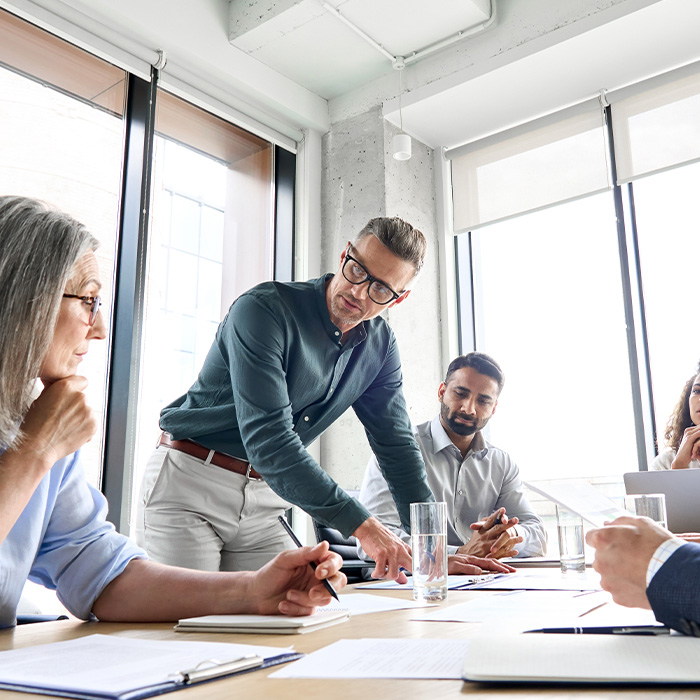 Business professionals discussing TM44 inspection requirements during a compliance meeting in a modern office.