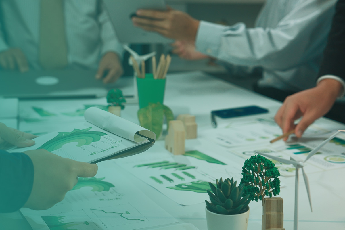 “Team collaborating around sustainability data and models during Stakeholder Engagement Workshops and Employee Surveys, with green charts, documents, and eco-themed materials on the table.”