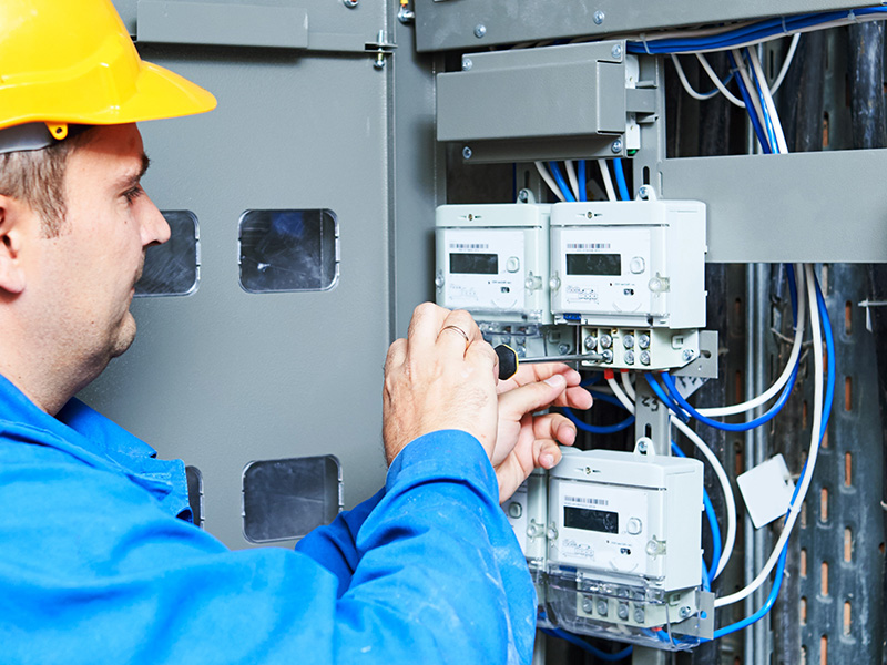Engineer in protective gear installing and maintaining AMR energy meters, highlighting the role of AMR energy meters and BMS audits in energy management.