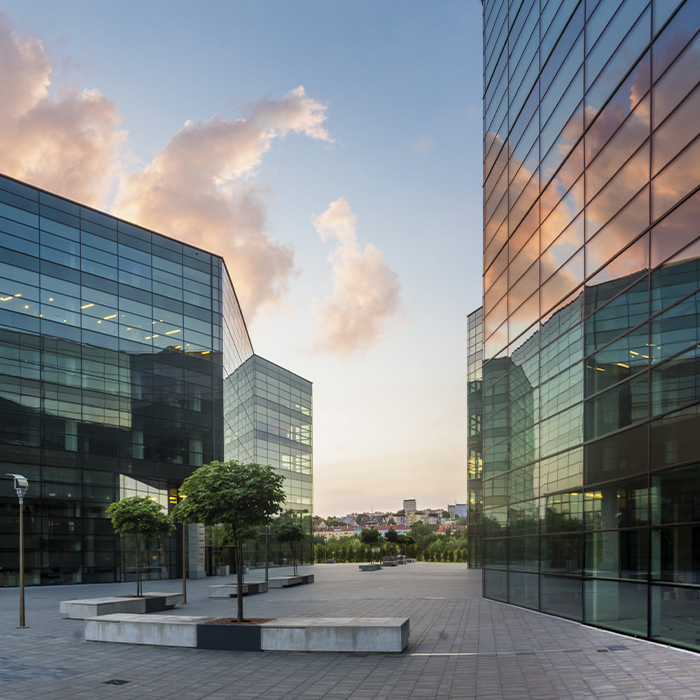 Modern glass-fronted office complex at sunset, symbolising the importance of a track and trace survey for commercial buildings in managing utilities and compliance.