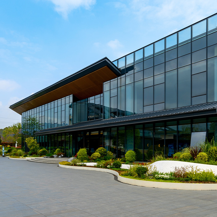 Modern glass-fronted office building with landscaped surroundings, representing the need for a track and trace survey for commercial buildings to map utilities accurately.