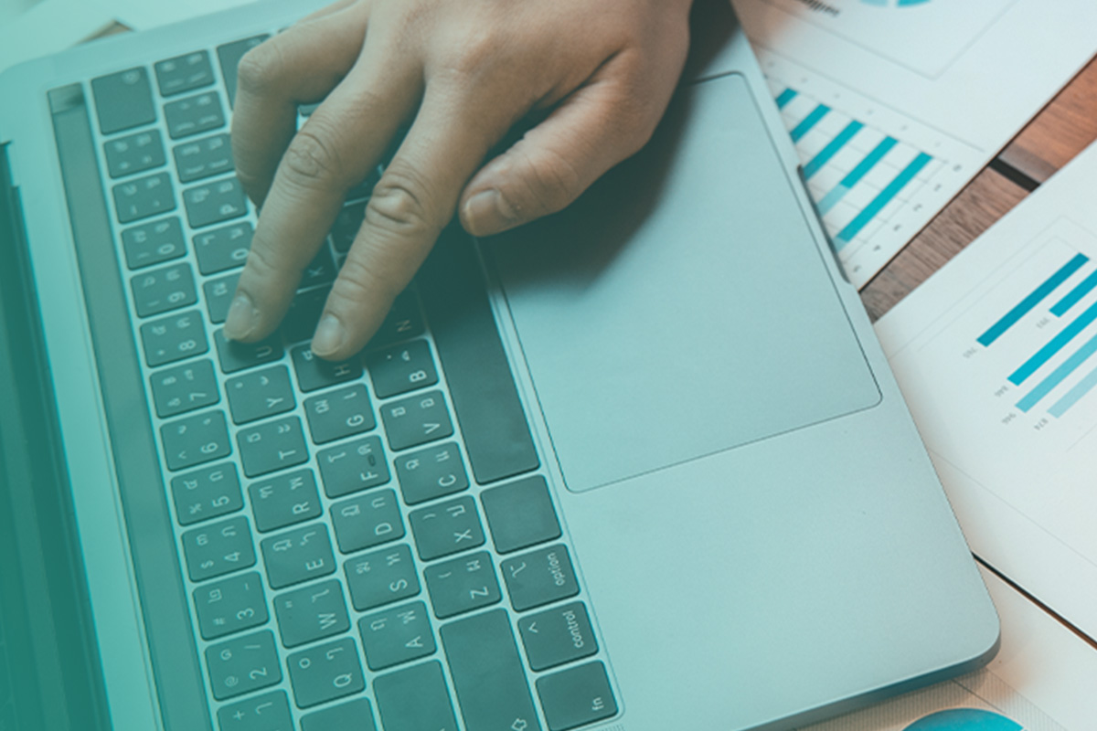 “Hand typing on a laptop beside energy data charts, representing ESOS Compliance Services for Phase 4 Reporting.”