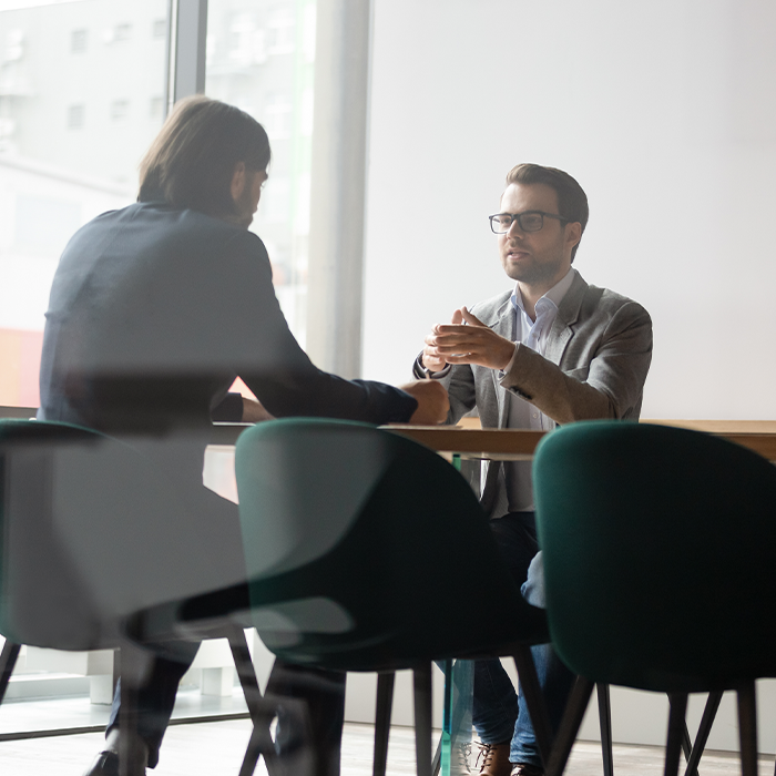 Two professionals in discussion at a table, representing a consultation about bill validation services.