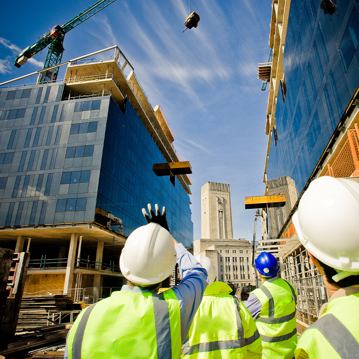 Construction workers on-site observing building progress, where EPC requirements will apply upon completion.