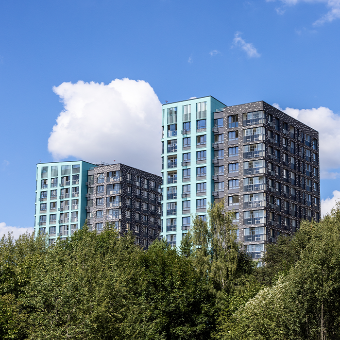 Modern residential towers surrounded by trees, representing buildings subject to MEES and EPC compliance requirements.