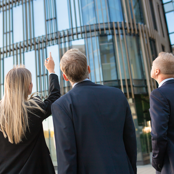 Business professionals inspecting a modern building exterior — discussing the implementation of AMR metering.