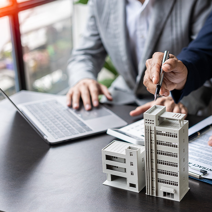 Business professionals discussing energy data next to commercial building models — illustrating AMR metering services for commercial energy monitoring.