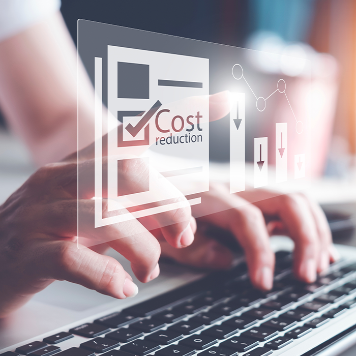 Hands typing on a laptop with a digital overlay reading "Cost reduction" and downward graph icons — illustrating savings from bill validation.