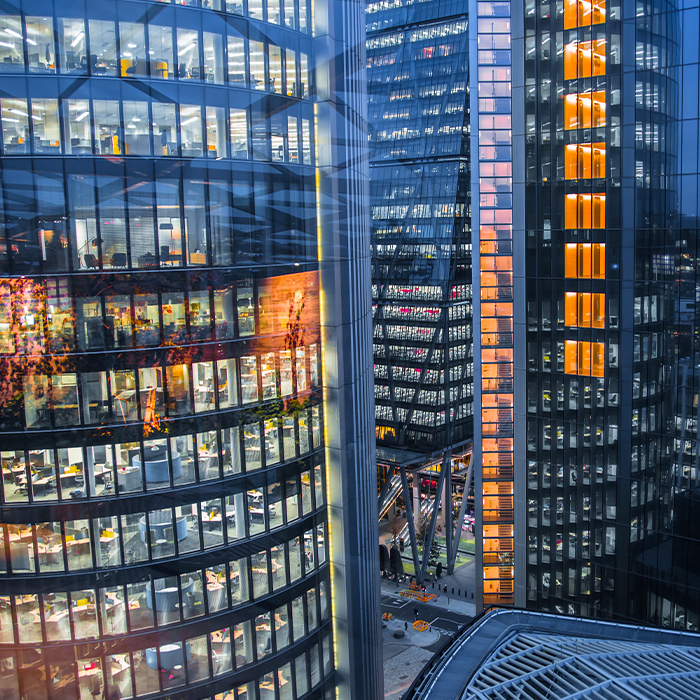 Evening view of illuminated high-rise office buildings in a modern financial district, representing the demand served by business electricity providers.