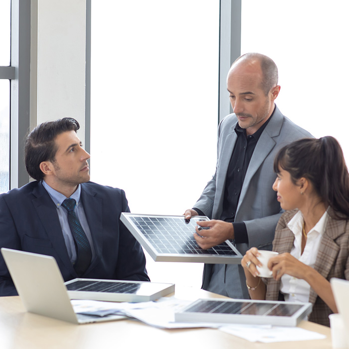 Three professionals in a meeting room discussing solar panel solutions, representing frequently asked questions about sustainable energy services.