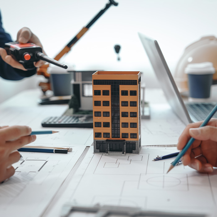 Architects reviewing a building model and plans, representing How to Decide – Questions to Ask Internally.