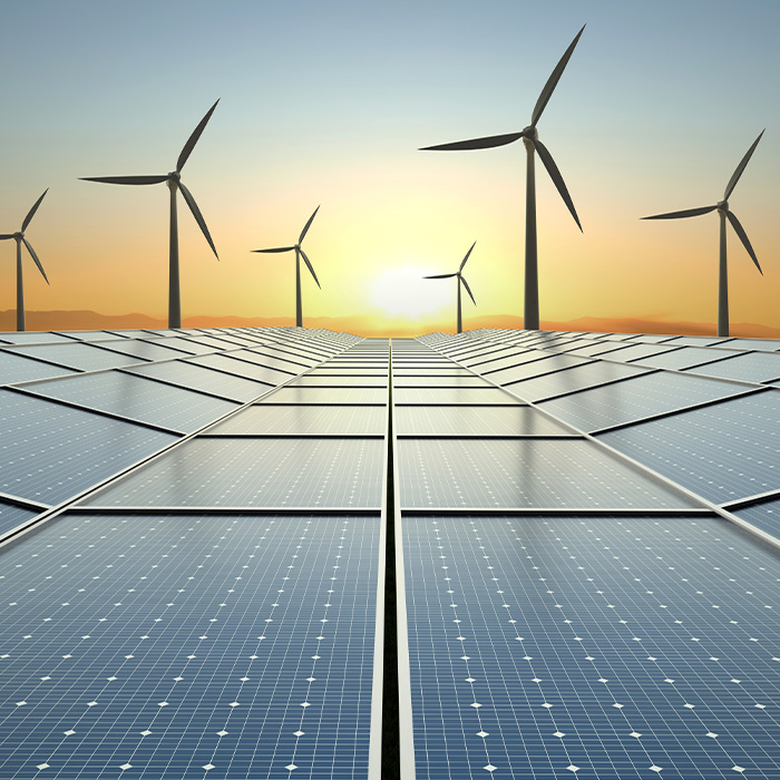 Solar panels and wind turbines at sunrise representing trends in What’s Shaping Energy Procurement in 2025.