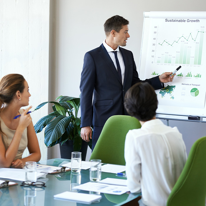 Business professional presenting a strategic energy procurement plan to colleagues in a meeting room with a growth chart on display.