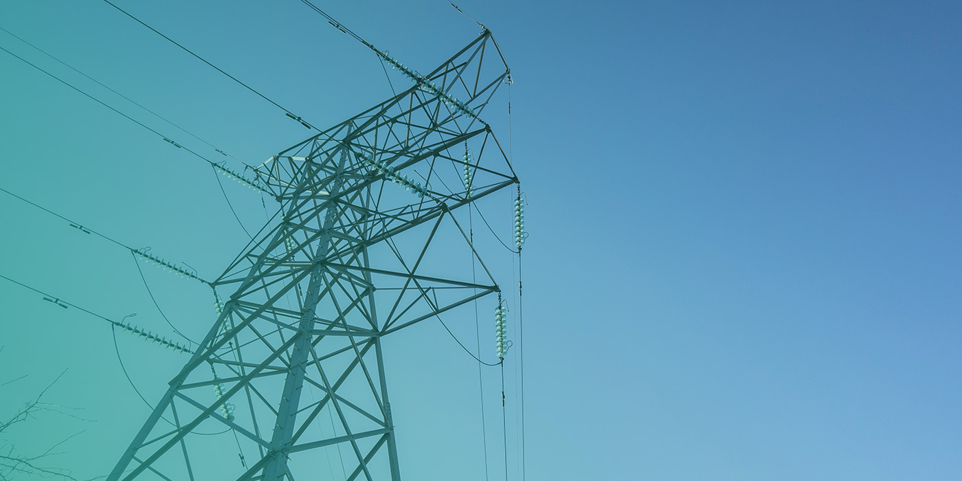 High-voltage electricity pylon against a clear blue sky, highlighting grid pressures and the importance of Energy Risk Management 2026 for business resilience.